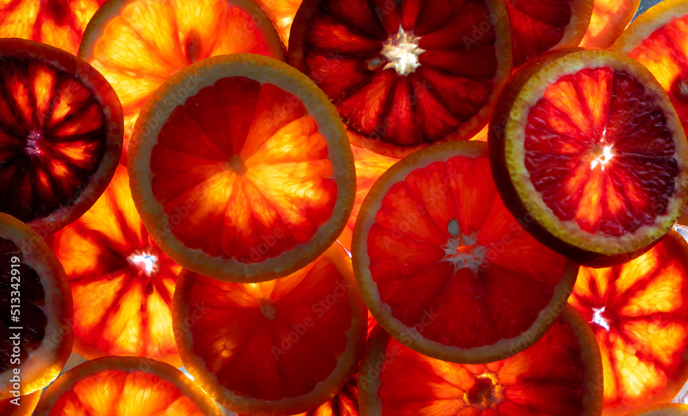 Red oranges fruit background. Sliced juicy orange. Food. Summer concept. Close-up on the light. Translucent.