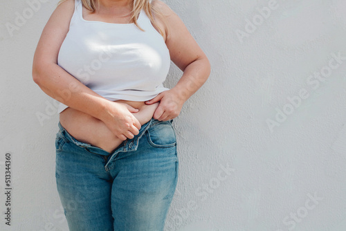 Foto Young woman with flabby belly and thick sides showing waist in unzipped jeans