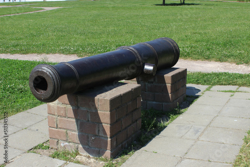 The barrel of an artillery gun standing on brick pedestals