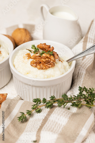 White rice pudding mold, whith milk or cream, cinnamon, whole walnuts and thyme stems on striped napkin. Serving a kheer