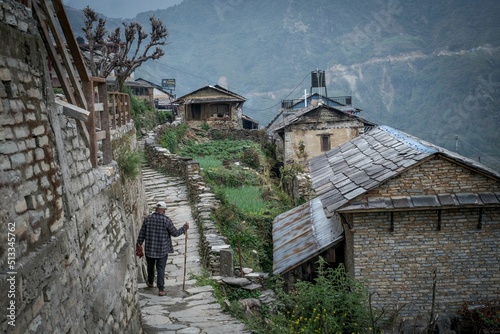 Man walking with a stick through the old Himalayan town of Ghandruk in Nepal, Asia photo