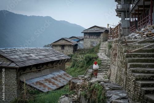 Lady walks carrying a big bag on her back through the Himalayan town of Ghandruk in Nepal, Asia photo