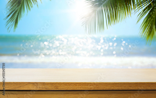 Empty wooden table over blurred sunny tropical beach background. Outdoor party mock up for design and product display.