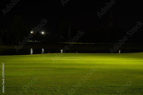 Beautiful dark night view of the golf course, Bunkers sand and green grass, garden background In the light of the spotlight underexposure view. Film camera look photo noise and Grain.