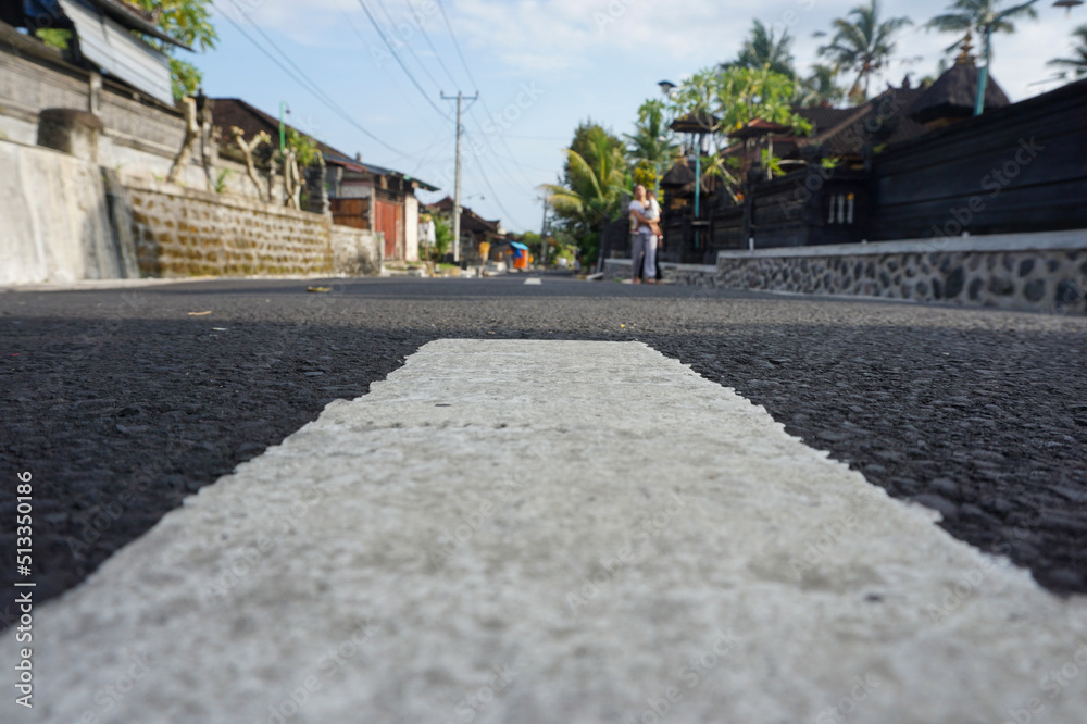 Paved village road. The road is still smooth and black. Equipped with road markings.