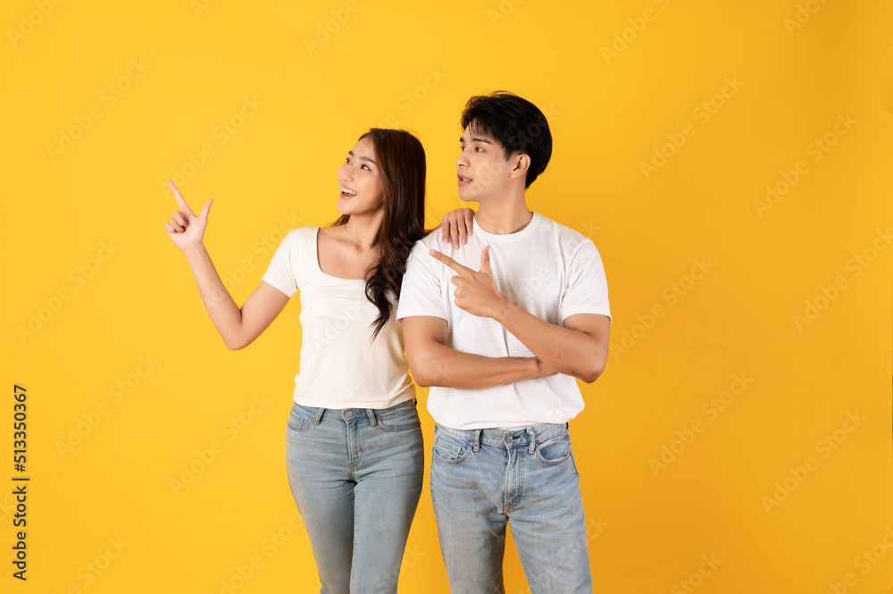 Couple of teenage asian boy and girl together isolate on yellow background pointing and surprise Couple of teenage asian boy and girl together isolate on yellow background pointing and surprise
