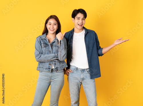 Two Young good looking asian couple using isolated on yellow background presenting to copy space