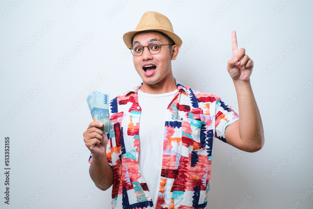 Young asian man holding money surprised with an idea or question pointing finger Young asian man holding money surprised with an idea or question pointing finger