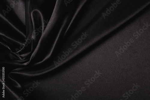 Abstract monochrome elegant luxury cloth background. Black color background with drapery and wavy folds of luxurious silk satin material. Top view