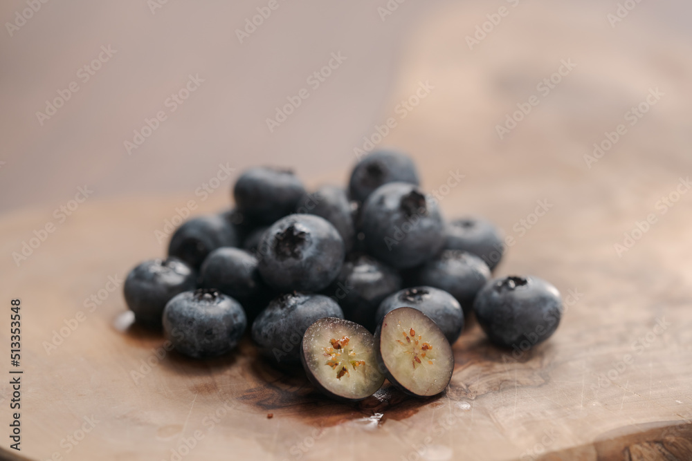 Fresh blueberries on wood board one berry is cut in halves Fresh blueberries on wood board one berry is cut in halves