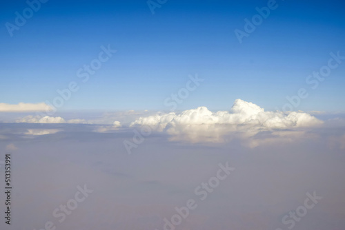 Cloudy sky. Beautiful sky with white fluffy cumulus clouds, natural abstract background. View from plane. Selective focus. © Marina_Nov