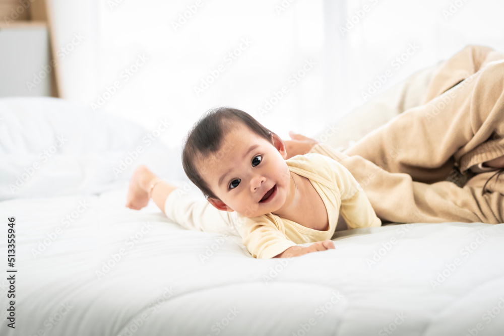 baby girl with asian mom smiling baby happily playing together in bed in the bedroom at home
