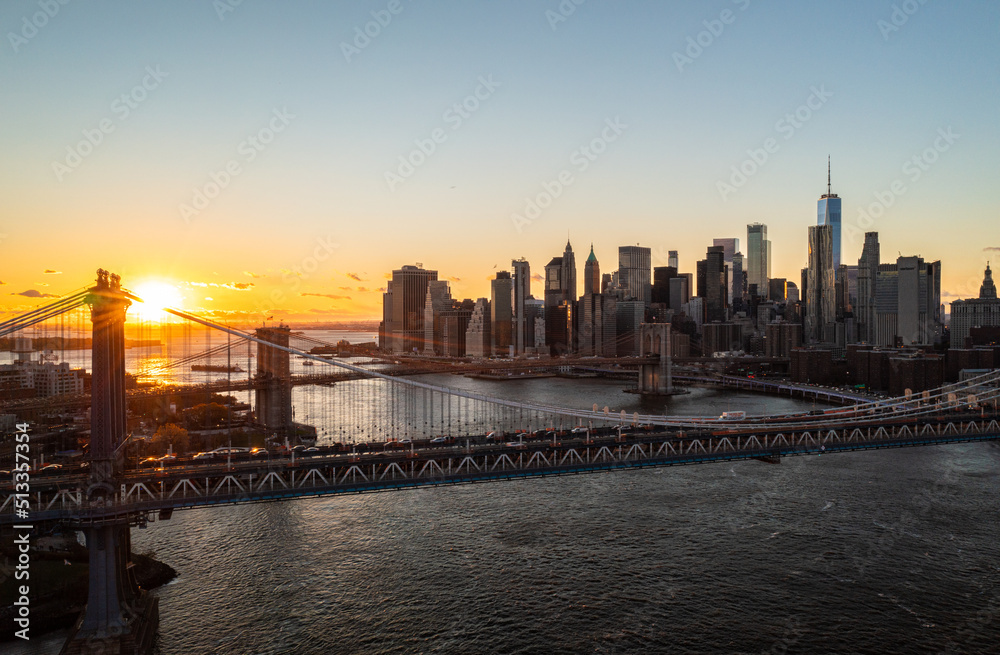 Aerial panoramic view of modern office towers on Lower Manhattan at sunset. Romantic evening shot of bridges over East river. Manhattan, New York City, USA