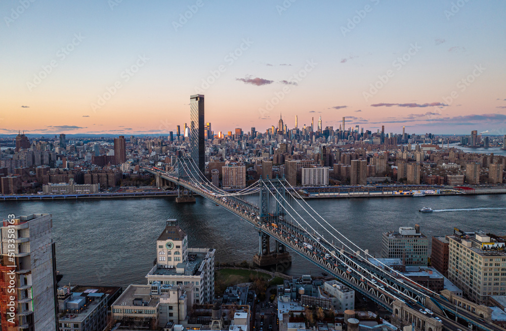 Famous cable stayed Manhattan bridge over East River at twilight. Urban boroughs and downtown skyscrapers in distance. Manhattan, New York City, USA