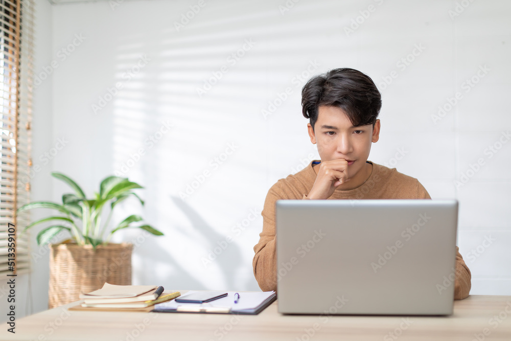 Freelancer Asian man looking at computer laptop screen concentrate and thinking with him job. Serious business man working at home having problem with job thinking to solve problem. Freelancer Asian man looking at computer laptop screen concentrate and thinking with him job. Serious business man working at home having problem with job thinking to solve problem.