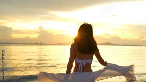Smiling attractive young asian woman bikini sexy with shawl on a seaside beach tropical resting and relaxation travel lifestyle, Happy female enjoy life playing and freedom at sunset. © Kiattisak