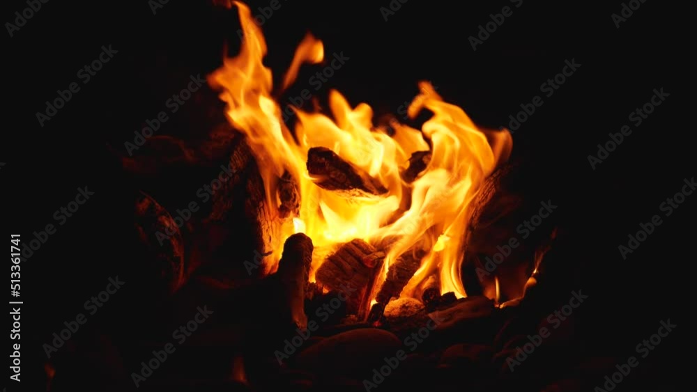 Slow motion of wood burning in the bright red and yellow flames of a campfire. Camera movement from bottom to top. Taking a break on a wild pebble beach while traveling Slow motion of wood burning in the bright red and yellow flames of a campfire. Camera movement from bottom to top. Taking a break on a wild pebble beach while traveling