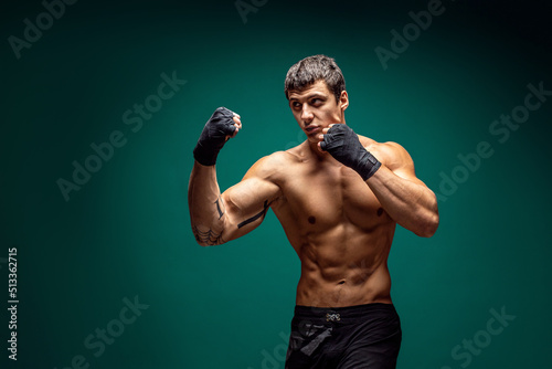 Side view of Male boxer training and practicing swing Isolated on green studio background. Concept of sport, healthy lifestyle © zamuruev