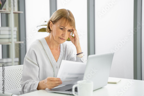 Stressed mature woman looking at debt document