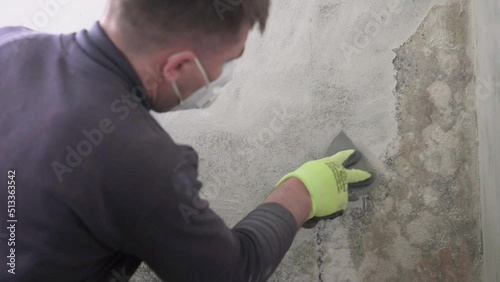 Removal of fungus and mold at home, peeling the first layer of fungus on the wall with a spatula.