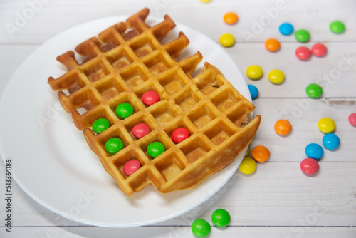 Kids food. Funny creative breakfast. Blgian waffles and colorful chocolate round candies. Selective focus photo