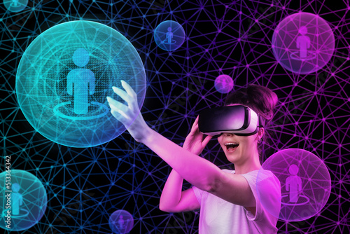 Portrait of young happy woman in VR glasses touch a sphere with symbol of person. Dark background with abstract mesh and neon light balls. The concept of 3D simulation, metaverse and cyber space