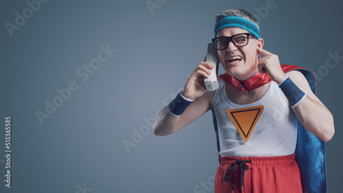 Funny superhero making a phone call using a cordless telephone photo