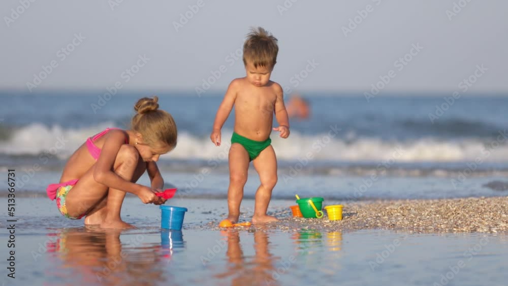 Older sister playing with younger brother aground near the shore on summer vacation Older sister playing with younger brother aground near the shore on summer vacation