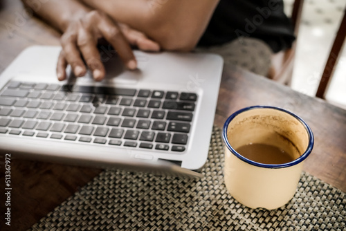 A Man Browsing Internet Using Laptop at Home Accompanied with a Glass of Coffee
