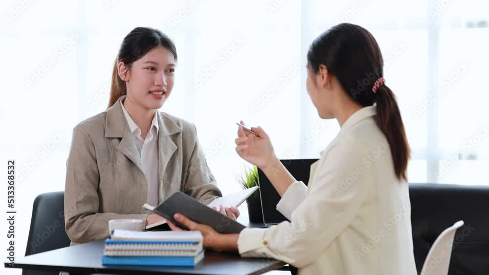 Two women sitting through white papers and talking, two business women discussing brainstorming and planning operations, form a partnership to form a startup company. Management of startup company. Two women sitting through white papers and talking, two business women discussing brainstorming and planning operations, form a partnership to form a startup company. Management of startup company.
