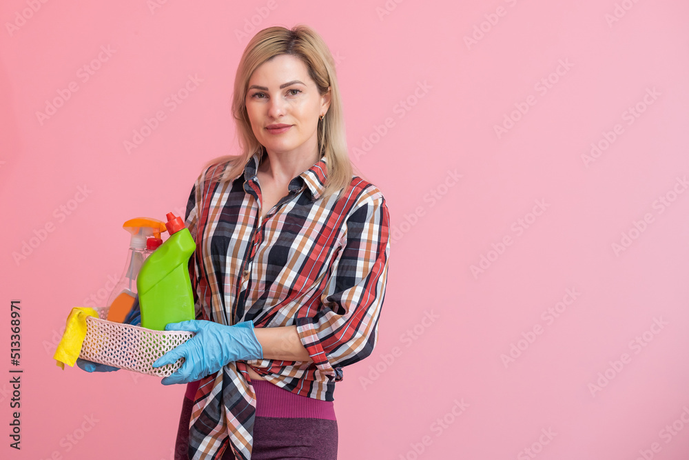 Bottles with household chemicals in a wicker basket in the hands of a caucasian woman. pink background. Place for text. Bottles with household chemicals in a wicker basket in the hands of a caucasian woman. pink background. Place for text.