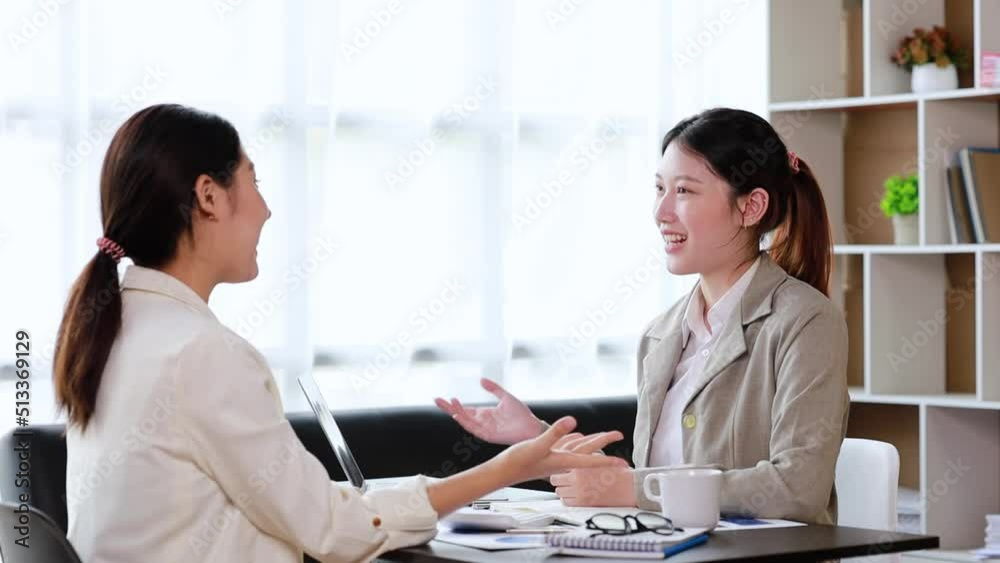Two women sitting through white papers and talking, two business women discussing brainstorming and planning operations, form a partnership to form a startup company. Management of startup company. Two women sitting through white papers and talking, two business women discussing brainstorming and planning operations, form a partnership to form a startup company. Management of startup company.