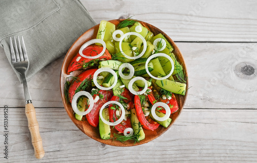 Fermented chopped natural vegetables: tomatoes, cucumbers and bell peppers in a wooden plate on a wooden table.