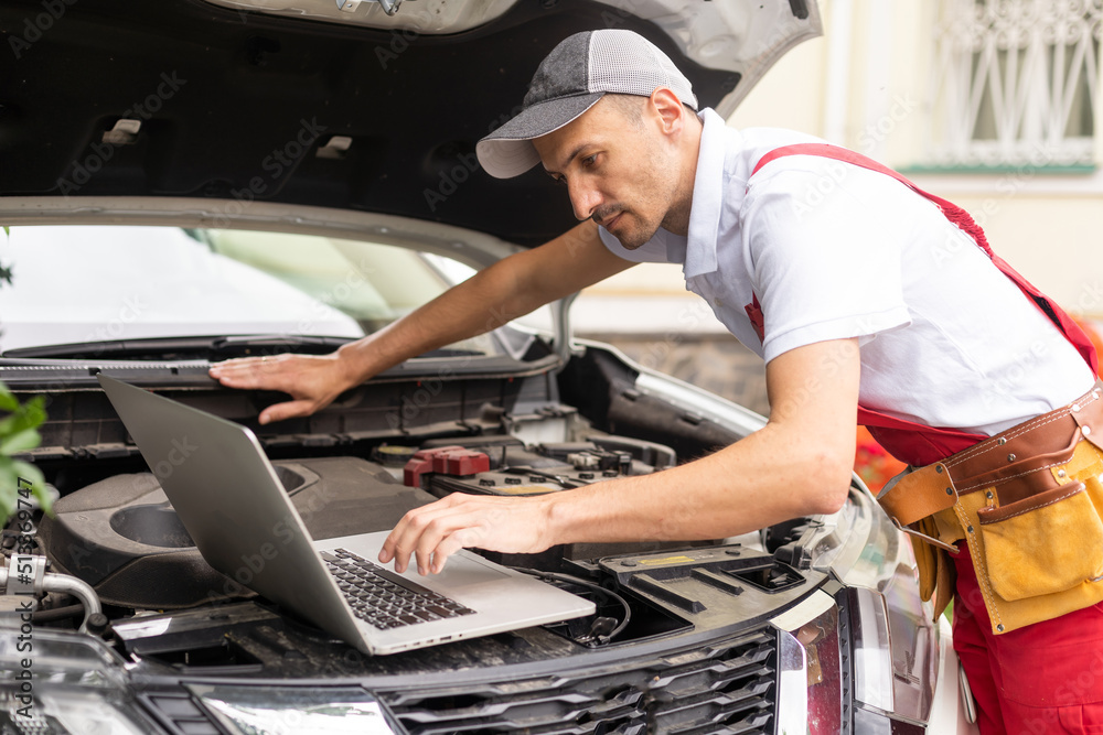 Car mechanic open hood to repair and check car problem system by laptop for maintenance and fixed in garage Car mechanic open hood to repair and check car problem system by laptop for maintenance and fixed in garage