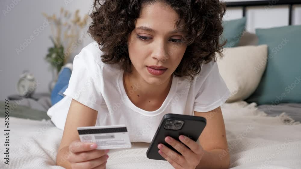 Close up smiling woman customer enters credit card code to pay gifts, online shopping via smartphone. Female shopper internet purchases or payments via mobile phone at home on bedroom. Online banking Close up smiling woman customer enters credit card code to pay gifts, online shopping via smartphone. Female shopper internet purchases or payments via mobile phone at home on bedroom. Online banking