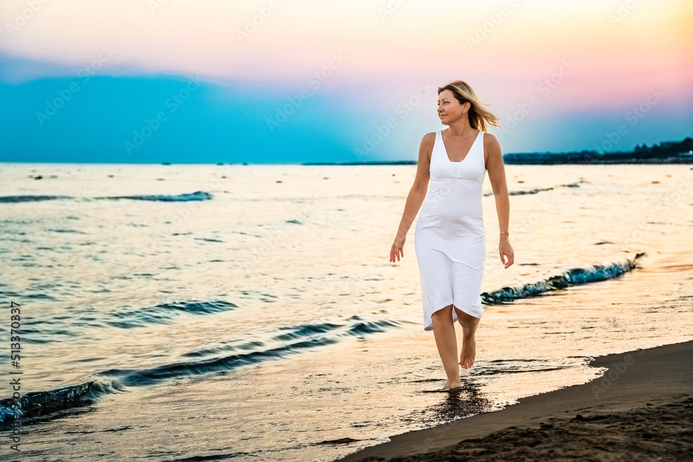 Woman walking on beach at sunset
