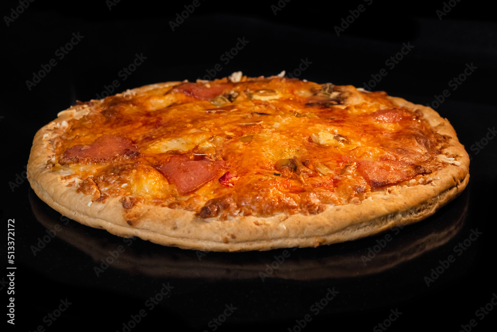 Burnt pizza with sausage, mushroom, pepper, cheese on tray in electric oven, black background. Italian cuisine, homemade bakery, fast food concept