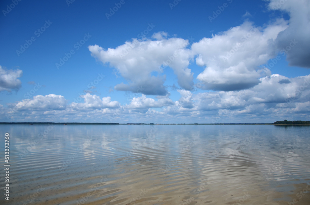 Peaceful landscape with calm water lake with blue sky with white clouds over the lake . Summer weekend on the lake concept. 