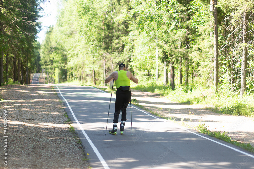 A man rides roller skis in a summer park.Fitness on the street. A man rides roller skis in a summer park.Fitness on the street.