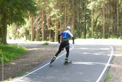 A man rides roller skis in a summer park.Fitness on the street.