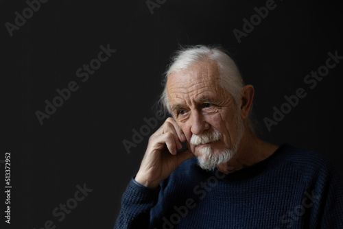 Low key studio portrait of sad beautiful gray hair old man.  photo