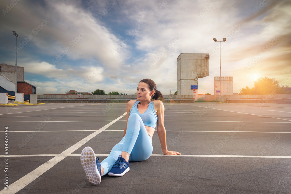 Sporty woman sitting and relaxing after exercise, urban background Sporty woman sitting and relaxing after exercise, urban background