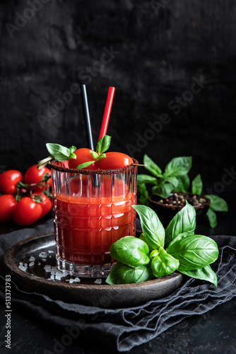 Bloody Mary cocktail served in glass with basil leaves and cherry tomatoes