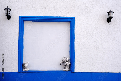 Blue empty frame on the wall and horse and woman figures in the lower corners of the frame. Two lamps in the upper corners. Empty space for design.