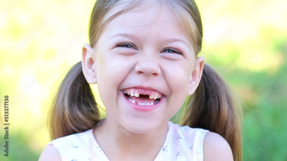 Portrait of laughing and happy toothless caucasian little girl of 6 years looking at camera outdoor summer Portrait of laughing and happy toothless caucasian little girl of 6 years looking at camera outdoor summer