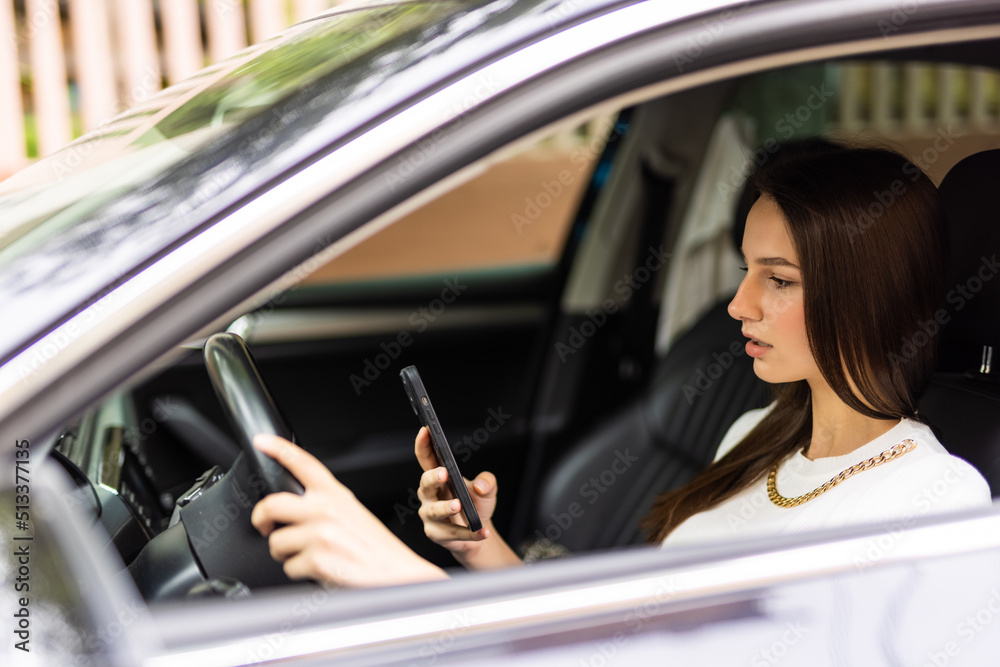 Business woman sitting in car and using her smartphone.