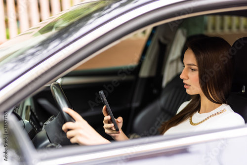 Business woman sitting in car and using her smartphone.
