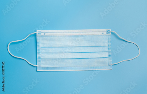 Medical mask. Blue medical mask with a white elastic band, isolated on a blue background.