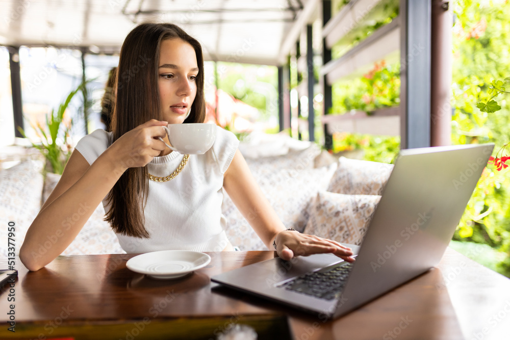 Young woman working on laptop in an outdoor cafe. Young woman working on laptop in an outdoor cafe.