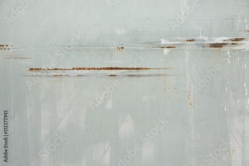 Fragment of an old iron sheet of pale green color. Brush marks are visible. The paint layer has horizontal scratches covered with rust. Background. Texture. photo